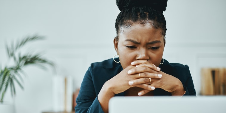 Shot of a young businesswoman frowning while using a laptop in a modern office.